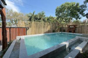 a swimming pool in a backyard with a wooden fence at Sufficient House in Nong Prue