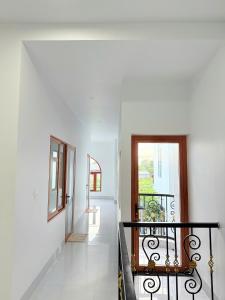 a hallway with white walls and a staircase with a window at HOMESTAY- Hưng Thịnh in Vạn Ninh