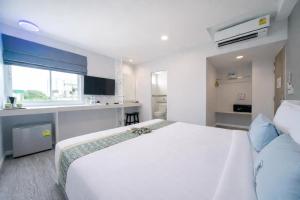 a bedroom with a large white bed and a kitchen at Peranakan Boutique Hotel - SHA Plus in Phuket