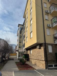 a tall yellow building next to a street at Apartman Lambros in Soko Banja