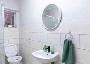 a white bathroom with a sink and a mirror at Deluxe on Main in Roodepoort