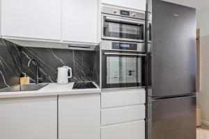 a kitchen with white cabinets and a stainless steel refrigerator at Prestige Center Warsaw Rooms Metro, AC, Smart TV, 2 Bathrooms in Warsaw