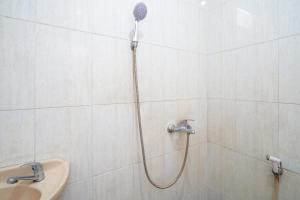 a shower in a white tiled bathroom with a sink at Rehat at Hotel Kurnia Karapitan in Bandung +19 photos