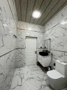a white bathroom with a toilet and a sink at Qax home in Qax