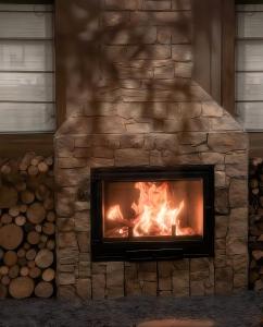 a stone fireplace with a fire in it at Shishe Spring Designer Homestay in Dujiangyan