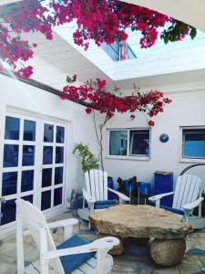 a patio with white chairs and a table with red flowers at Greek Style Bed & Breakfast in Al Manashsh