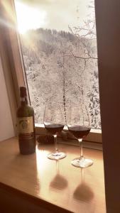 two glasses of wine sitting on a table next to a window at Apartments Aurelius in Jahorina