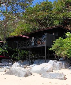 a house on the beach with rocks in front of it at Melina Beach Resort in Tioman Island