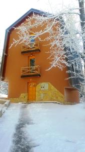 a house covered in snow with a tree at Apartments Aurelius in Jahorina