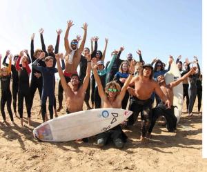 a group of people posing on the beach with their surfboards at Natural Surf Morocco in Tamraght Ouzdar
