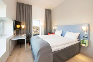 a hotel room with a bed and a desk and a window at Scandic Lerkendal in Trondheim +39 photos