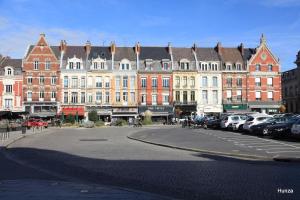 a group of buildings with cars parked in a parking lot at La Golden Suite in Cambrai