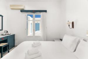ein weißes Schlafzimmer mit einem Bett und einem Fenster in der Unterkunft Paros Inn Seafront by GHH in Logaras
