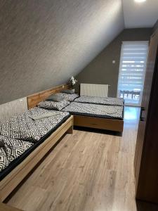 two beds in a room with wooden floors at Zajer Apartment Ház in Hajdúszoboszló