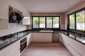 a kitchen with white cabinets and a sink and windows at Vantara Private Villa Chiang Mai in Chiang Mai