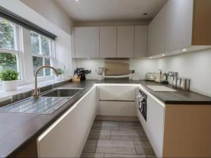a kitchen with white cabinets and a sink at Bumblebee Cottage, Aysgarth Falls in Aysgarth