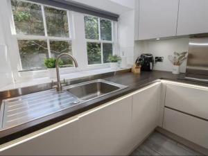 a kitchen with a sink and two windows at Bumblebee Cottage, Aysgarth Falls in Aysgarth +5 photos