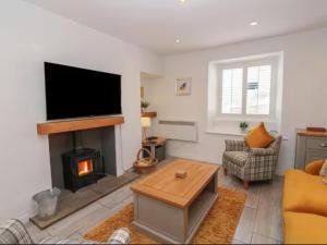 a living room with a fireplace and a flat screen tv at Bumblebee Cottage, Aysgarth Falls in Aysgarth