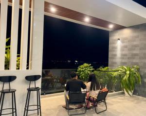 a man and a woman sitting on a balcony looking out at night at Ancor Homestay in Phan Rang–Tháp Chàm