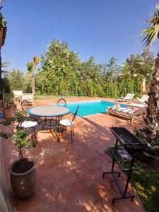 a patio with a table and chairs next to a pool at فيلا رياض عمران in Douar Blidene