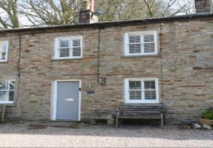 a brick building with a blue door and white windows at Bumblebee Cottage, Aysgarth Falls in Aysgarth