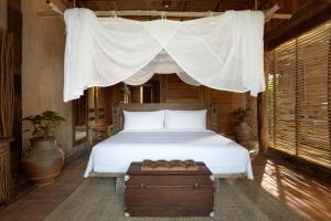 a bedroom with a white bed with a canopy at Dinso Resort & Villas Ko Chang, Vignette Collection by IHG in Ko Chang