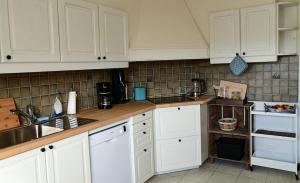 a kitchen with white cabinets and a sink at Cosy farmhouse with sauna in Sint-Truiden
