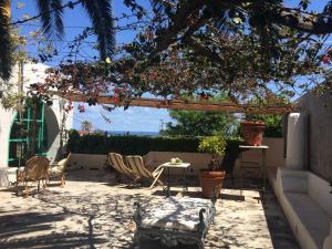 a patio with chairs and a table and a tree at La Locanda del Barbablù in Stromboli