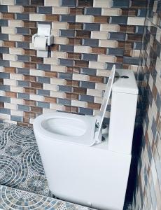 a white toilet in a bathroom with a tile wall at AnKeS Lodge in Sunyani +26 photos