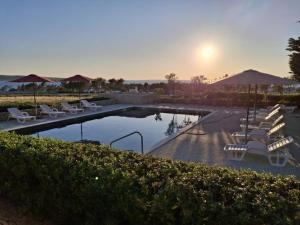 a swimming pool with chairs and umbrellas and the sunset at Bella Vista Blu apartman s pogledom na more, Povljana, otok Pag in Povljana