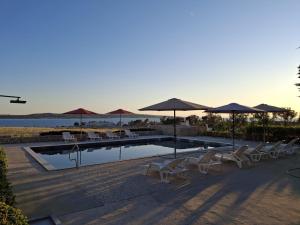 a swimming pool with chairs and umbrellas and a beach at Bella Vista Blu apartman s pogledom na more, Povljana, otok Pag in Povljana
