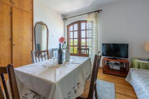 a dining room with a table with a vase of flowers on it at Apartments Ivan in Kampor