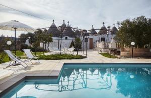 a swimming pool with two chairs and an umbrella at Trullo Dei Fiori in Cisternino