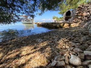 a rocky shore with a boat in the water at House Kornati Robinzon in Sit