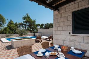 a patio with a table and chairs and a pool at House Sandra in Lumbarda
