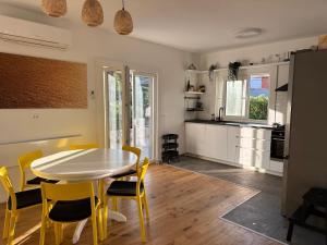 a kitchen and dining room with a white table and yellow chairs at House Pavicic in Poljica