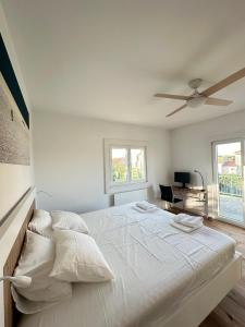 a white bedroom with a large bed with a ceiling fan at House Pavicic in Poljica