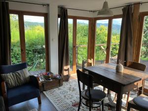 a dining room with a table and chairs and windows at Csillagfény Házikó in Nagymaros