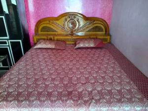 a bed with a wooden headboard in a room at Naveen Homestay in Amroha