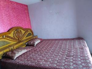 a bedroom with a bed with a pink wall at Naveen Homestay in Amroha