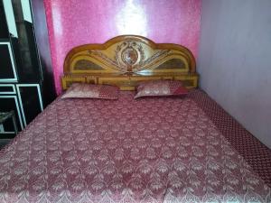 a bedroom with a wooden bed in a pink wall at Naveen Homestay in Amroha