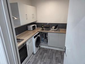 a small kitchen with a sink and a washing machine at Modern 1-Bed in Wolverhampton City Centre in Wolverhampton +9 photos