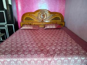 a bedroom with a wooden bed with pink walls at Naveen Homestay in Amroha