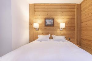 a bedroom with a large white bed with wooden walls at Résidence Les Chalets du Forum - Courchevel 1850 in Courchevel