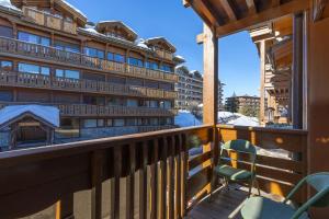 a balcony with a chair and a building at Résidence Les Chalets du Forum - Courchevel 1850 in Courchevel