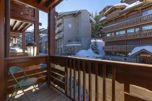 a wooden balcony with a chair and a building at Résidence Les Chalets du Forum - Courchevel 1850 in Courchevel +28 photos