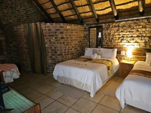 a bedroom with two beds and a brick wall at Die Kliphuisie Gastehuis in Vryburg