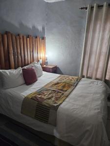 a bedroom with a large bed with a wooden headboard at Die Kliphuisie Gastehuis in Vryburg