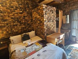 a bedroom with a bed in a brick wall at Die Kliphuisie Gastehuis in Vryburg