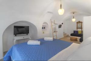 a white room with a blue bed with a tv at Casa View in Akrotiri